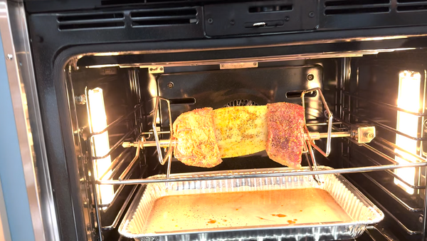 A pineapple roast cooking on a rotisserie